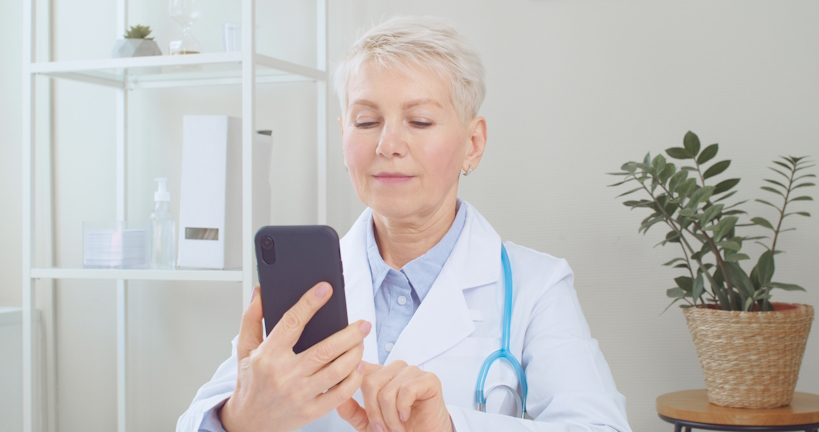 Senior doctor using smartphone and remote telehealth medical app