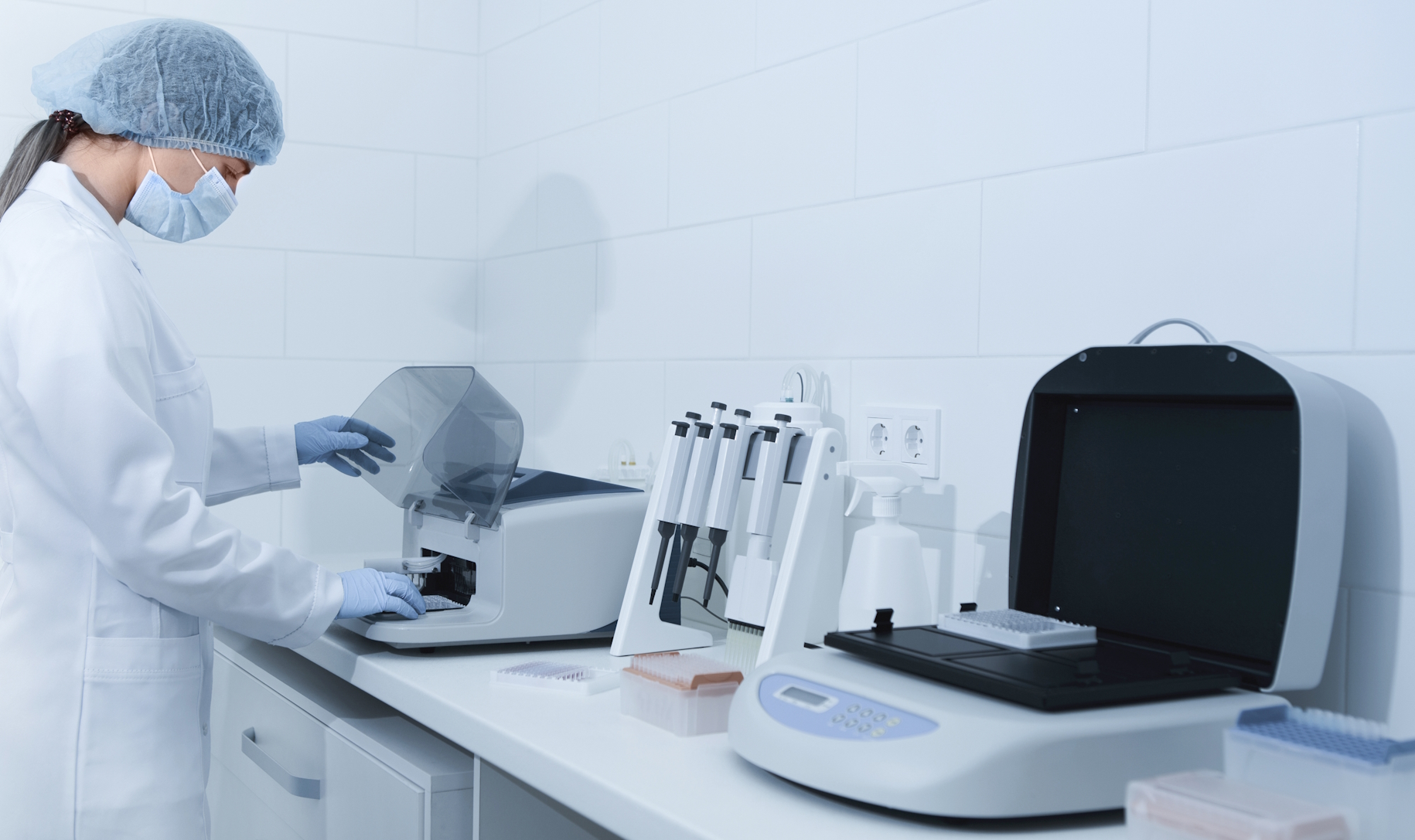 Young woman working in modern laboratory and using analyzer